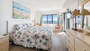 A bedroom with a bed, a dresser, a chair, a desk, a lamp, and a painting. - XPLORIE ACTIVITIES & LINENS INCLUDED*! Direct Oceanfront 2 bedroom (enclosed den converted to a 3rd bedroom with new double bed & pocket door) 2 bath condo. (Ocean City)