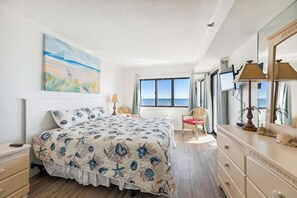 A bedroom with a bed, a dresser, a chair, a desk, a lamp, and a painting.