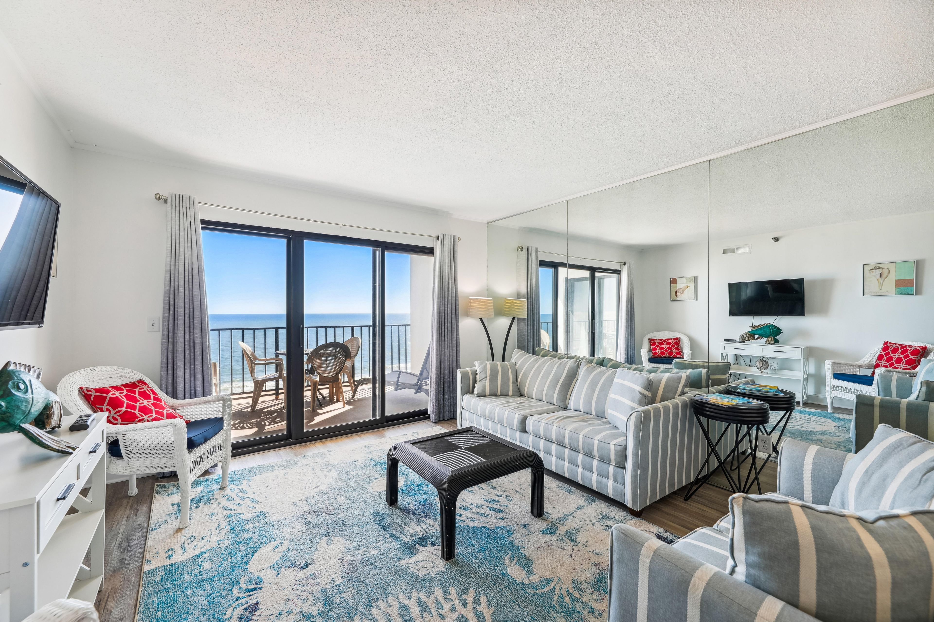 Un vaste espace de vie avec un balcon donnant sur la mer, aménagé avec un canapé, des fauteuils et une table basse.