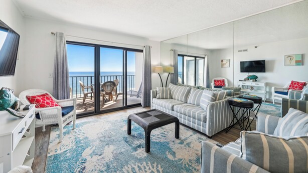 A living room with a sofa, armchairs, a coffee table, and a TV. There is a balcony with a view of the sea. - XPLORIE ACTIVITIES & LINENS INCLUDED*! Direct Oceanfront 2 bedroom (enclosed den converted to a 3rd bedroom with new double bed & pocket door) 2 bath condo. (Ocean City)