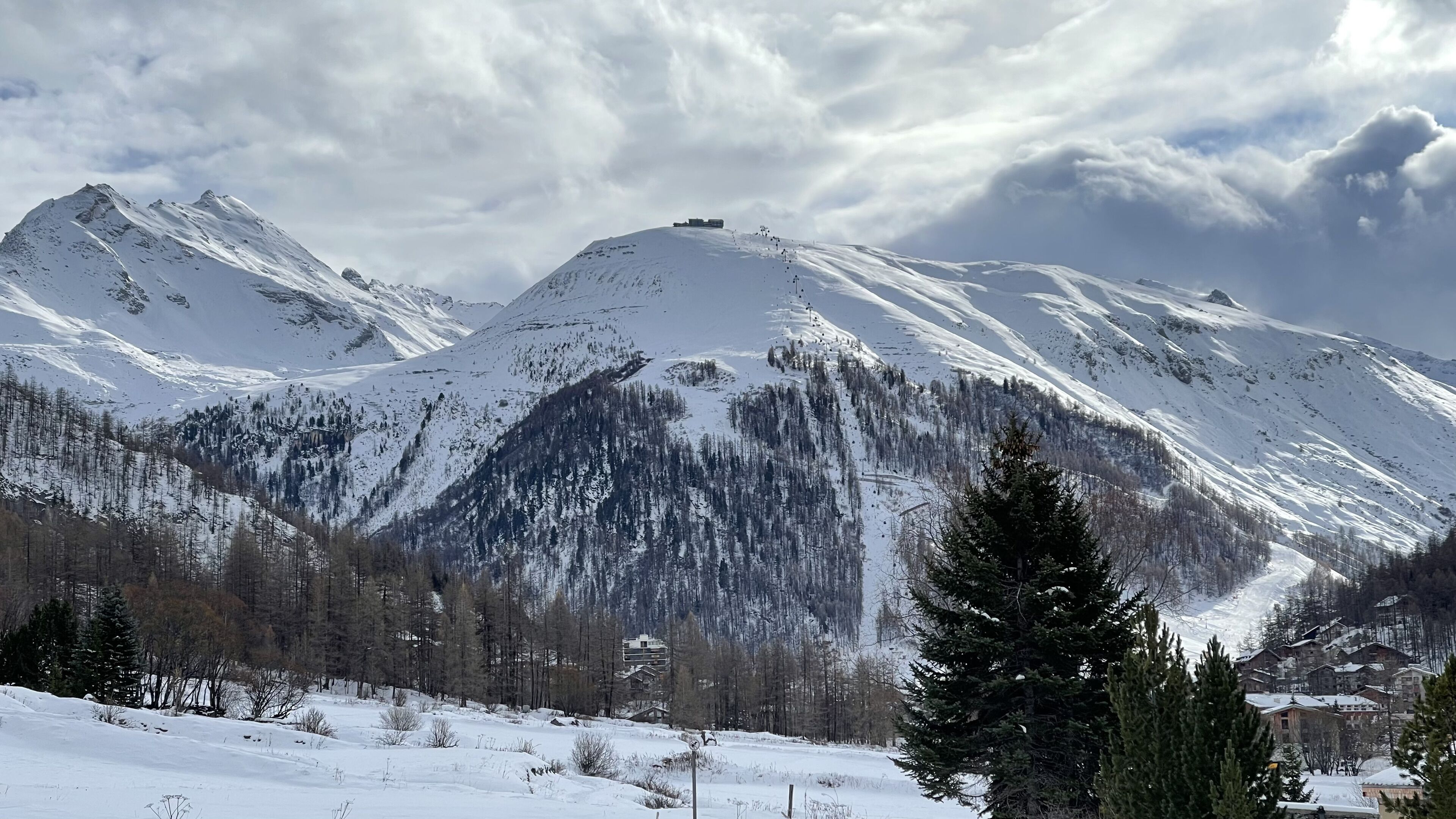 Eine verschneite Berglandschaft mit einem Skigebiet und Gebäuden am Fuße.