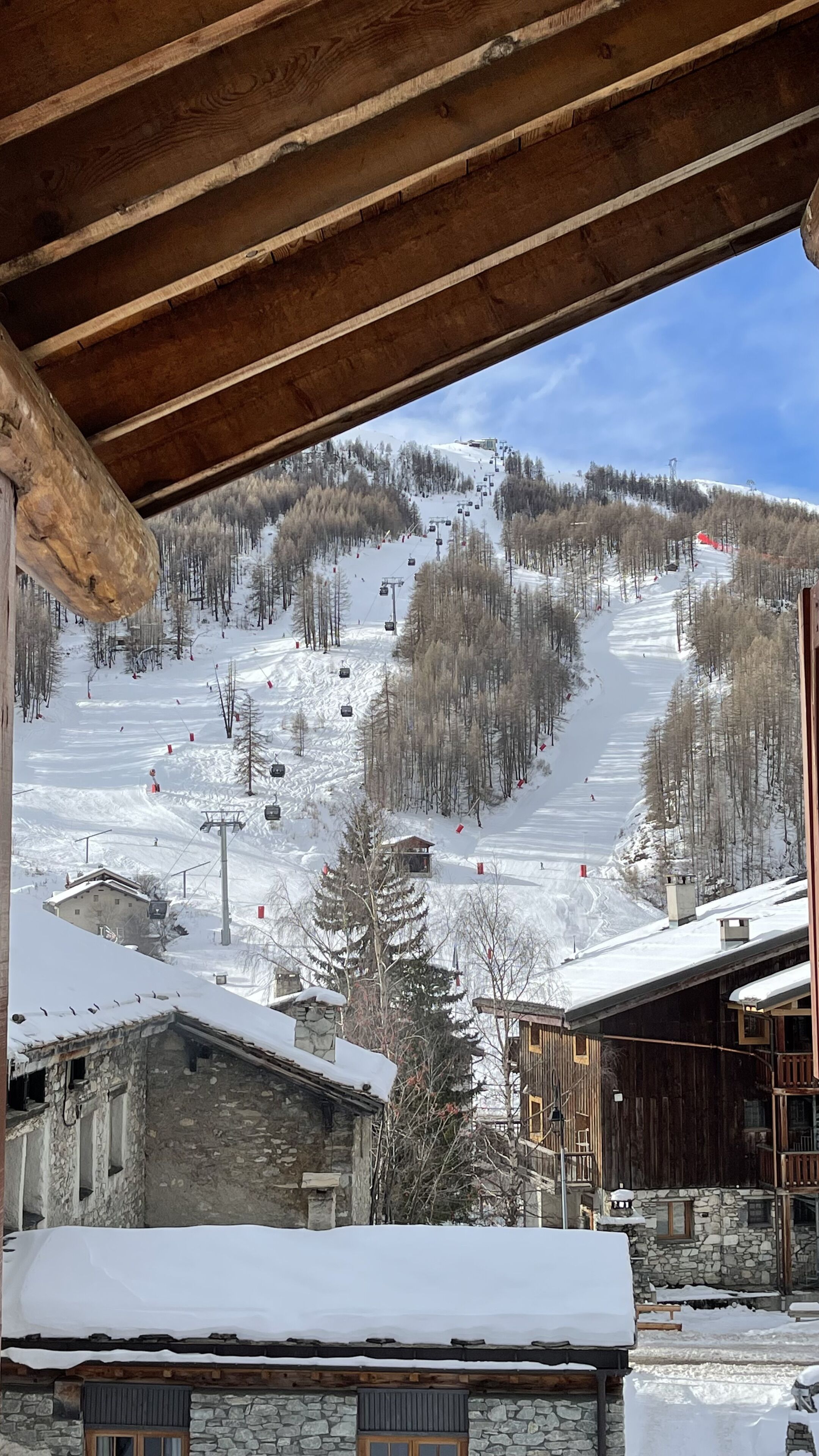 Un centro de esquí con edificios de madera, una ladera cubierta de nieve y un telesilla.