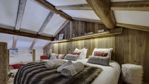 Un dormitorio acogedor con techo de madera, una manta de piel en la cama y una alfombra roja.