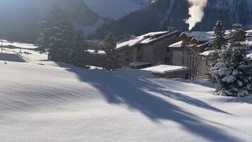Paesaggio innevato con un edificio dotato di tetto spiovente e diverse finestre.