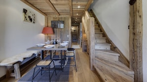 Un interior de madera con una mesa de comedor preparada para cuatro, un banco y una escalera.