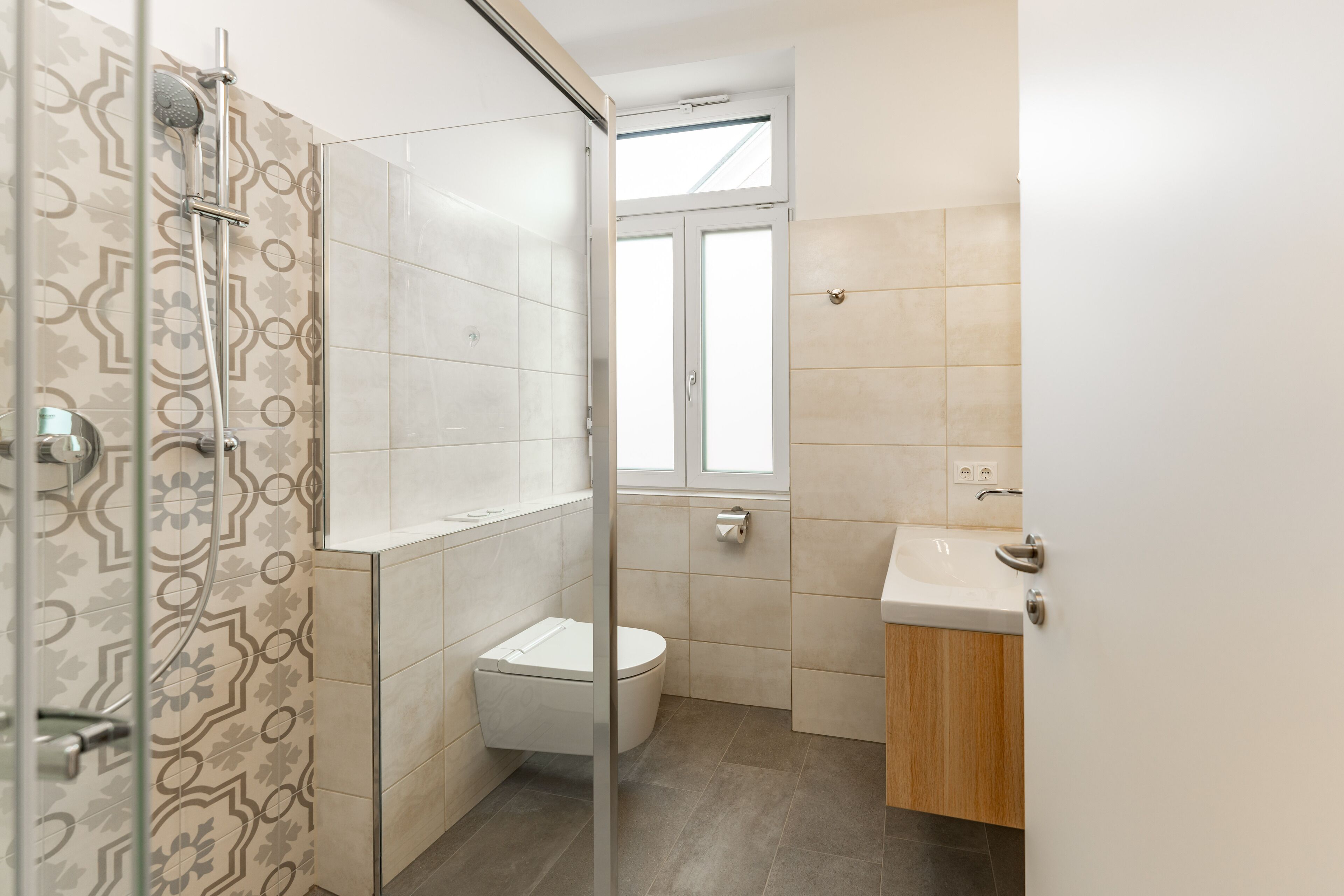A modern bathroom with a shower, toilet, and sink.