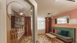 A reception area with a check-in counter, a sofa with cushions, a lamp, and a mirror on the wall. - Villa Elisa (Salzburg)