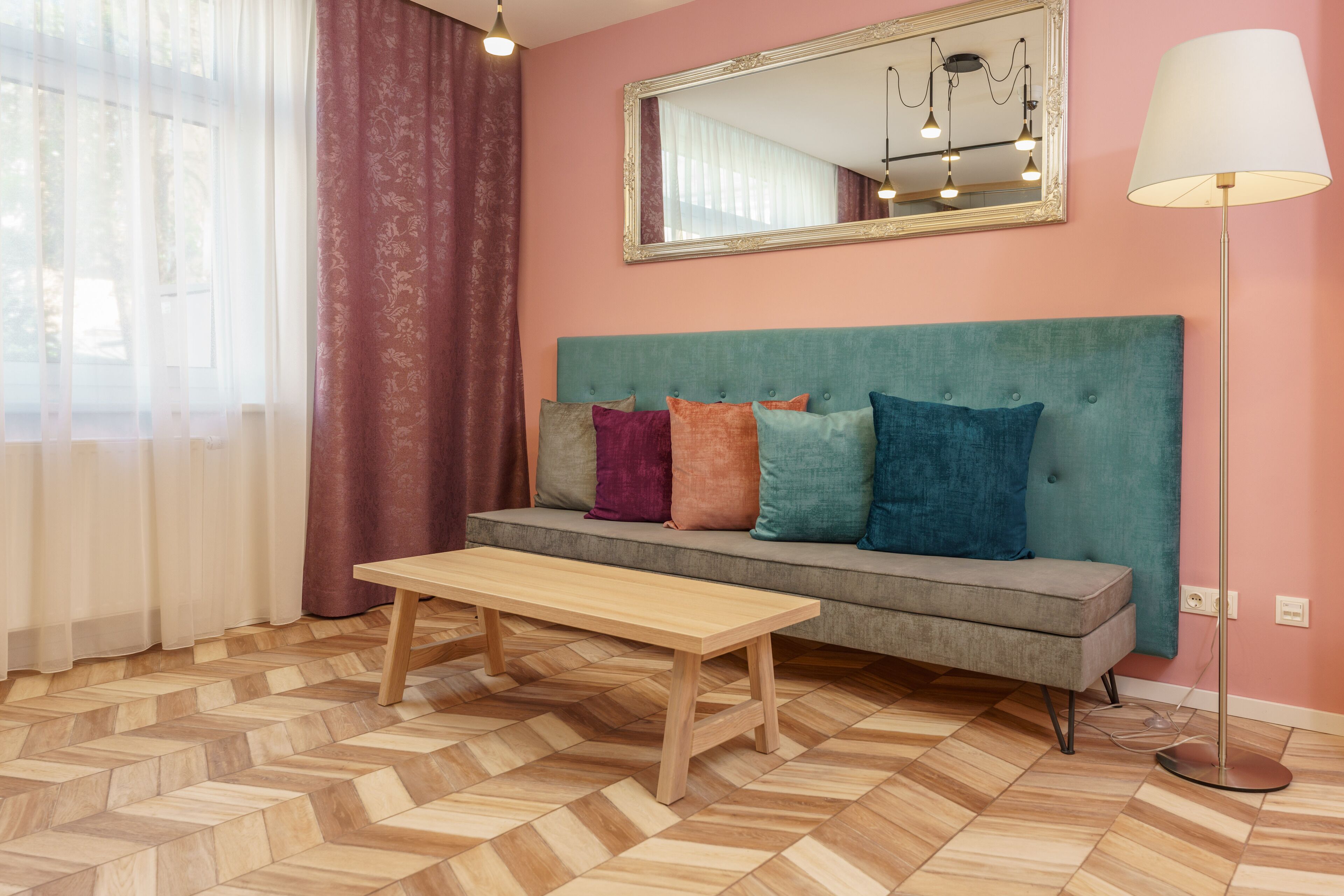 A room with a sofa, a wooden coffee table, a mirror, and a floor lamp.