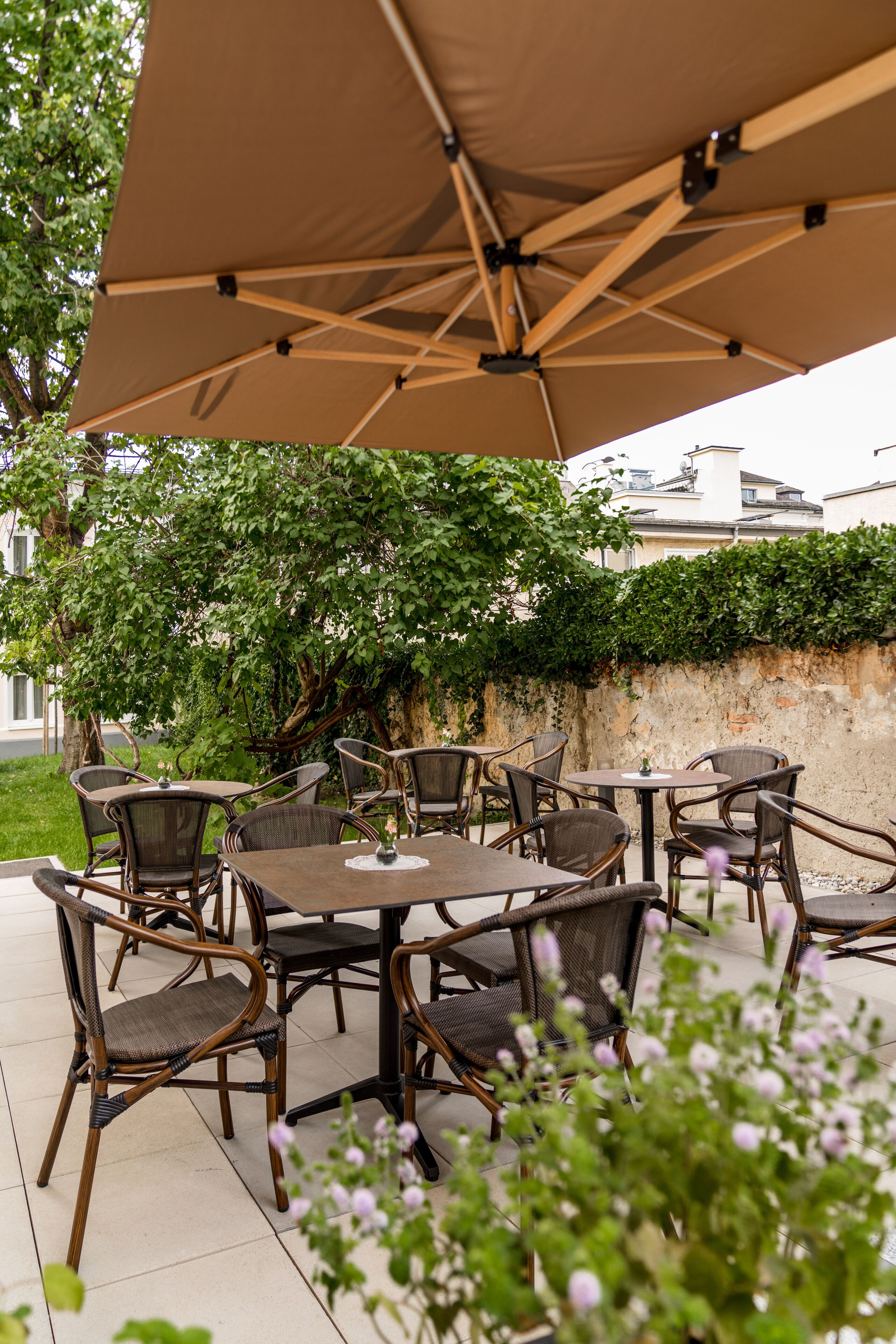 An outdoor patio with wicker furniture and a large umbrella providing shade.