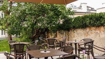 An outdoor patio with wicker furniture and a large umbrella providing shade.