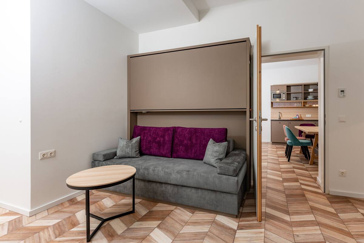 A modern living room with a grey sofa, a wooden coffee table, and a herringbone-patterned floor.