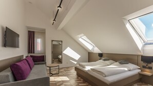 A modern bedroom with a large bed, a sofa, a small table, and a TV. - Villa Elisa (Salzburg)