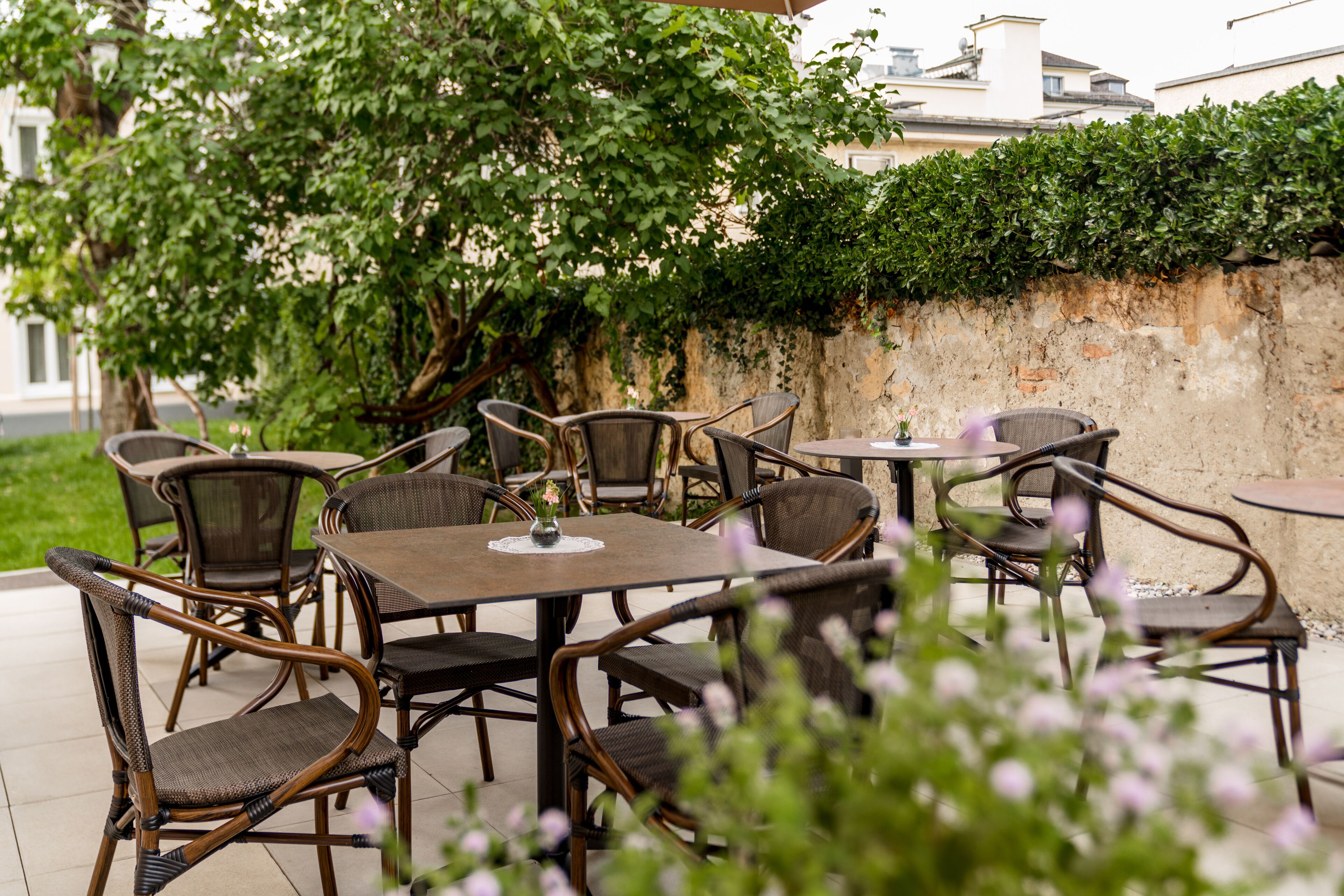 An outdoor patio with wicker furniture and a view of a building in the background.