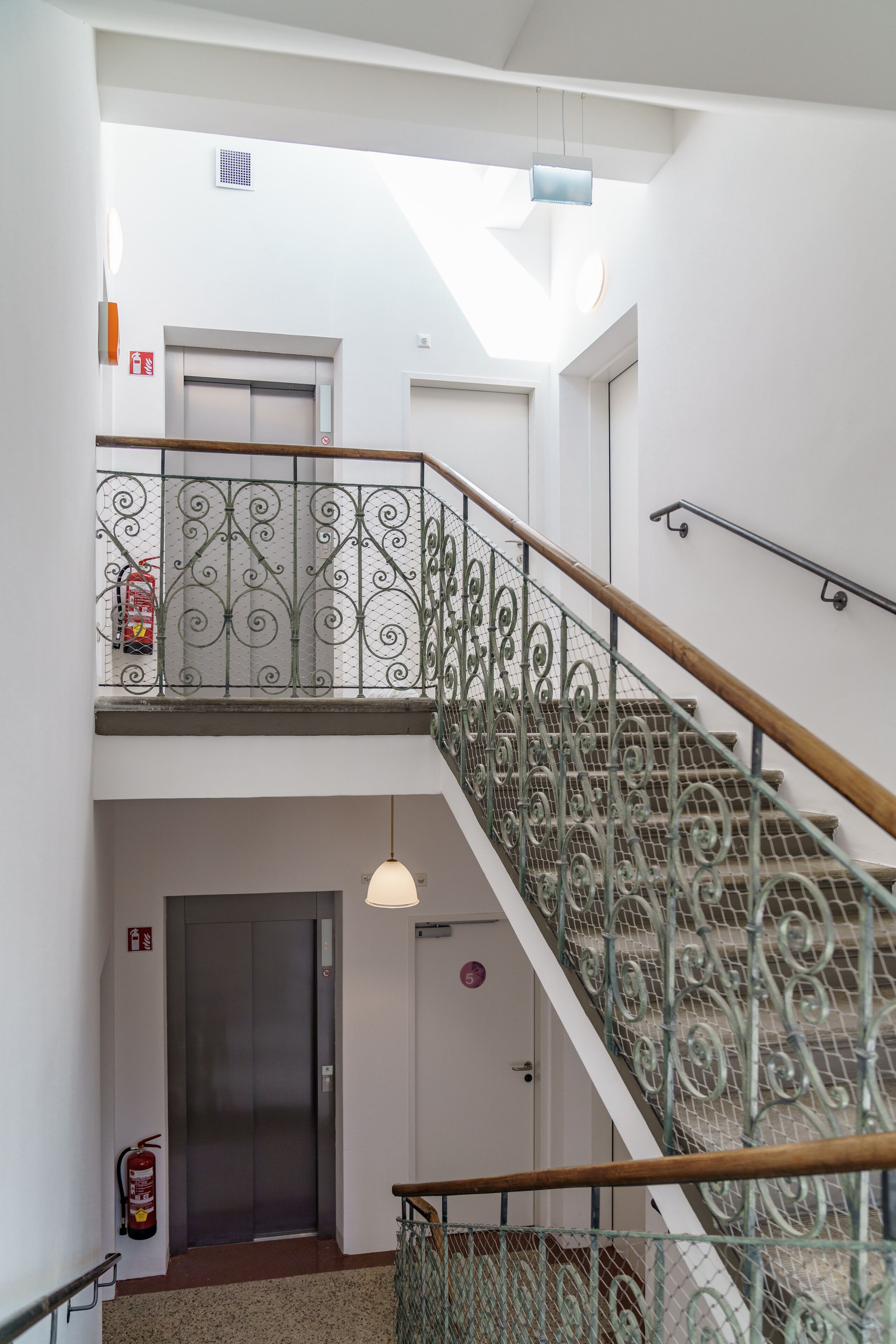 A multi-level interior with a staircase, a fire extinguisher, and a door.