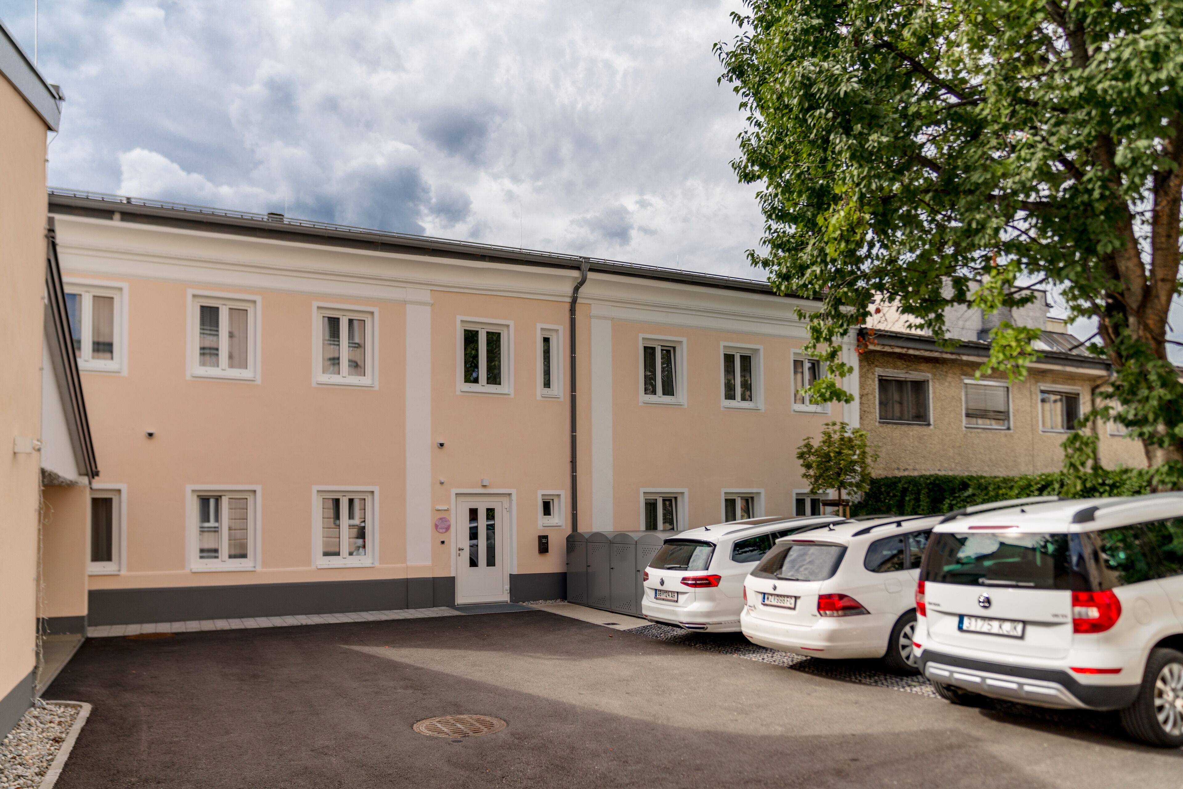 A row of white cars parked in front of a building with multiple windows and a door.