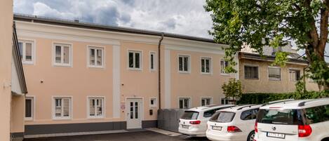 A row of white cars parked in front of a building with multiple windows and a door.