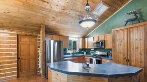 A kitchen with wooden cabinets, a stainless steel refrigerator, a microwave, and a large island with a coffee machine. - Private Hot Tub | Mountain Retreat | ATV's | Close to Wolf Creek Ski Area (South Fork)