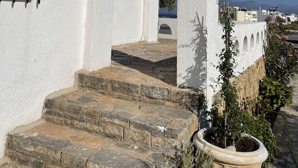 A white building with a stone staircase leading to an arched doorway.
