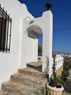 A white building with a stone staircase leading to an arched doorway.