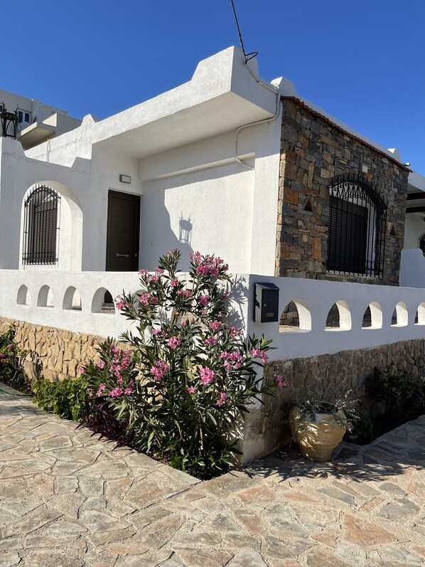 A white building with a stone facade, arched windows, and a door.
