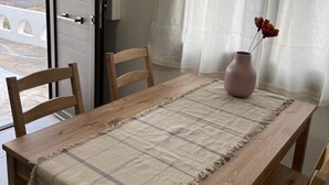 A dining table with a checkered tablecloth, wooden chairs, and a vase with dried flowers.