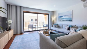 A modern living room with a sofa, coffee table, and a view of the balcony.
