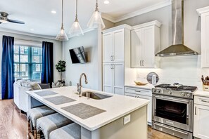 Una cocina moderna con una isla central, electrodomésticos de acero inoxidable y armarios blancos.