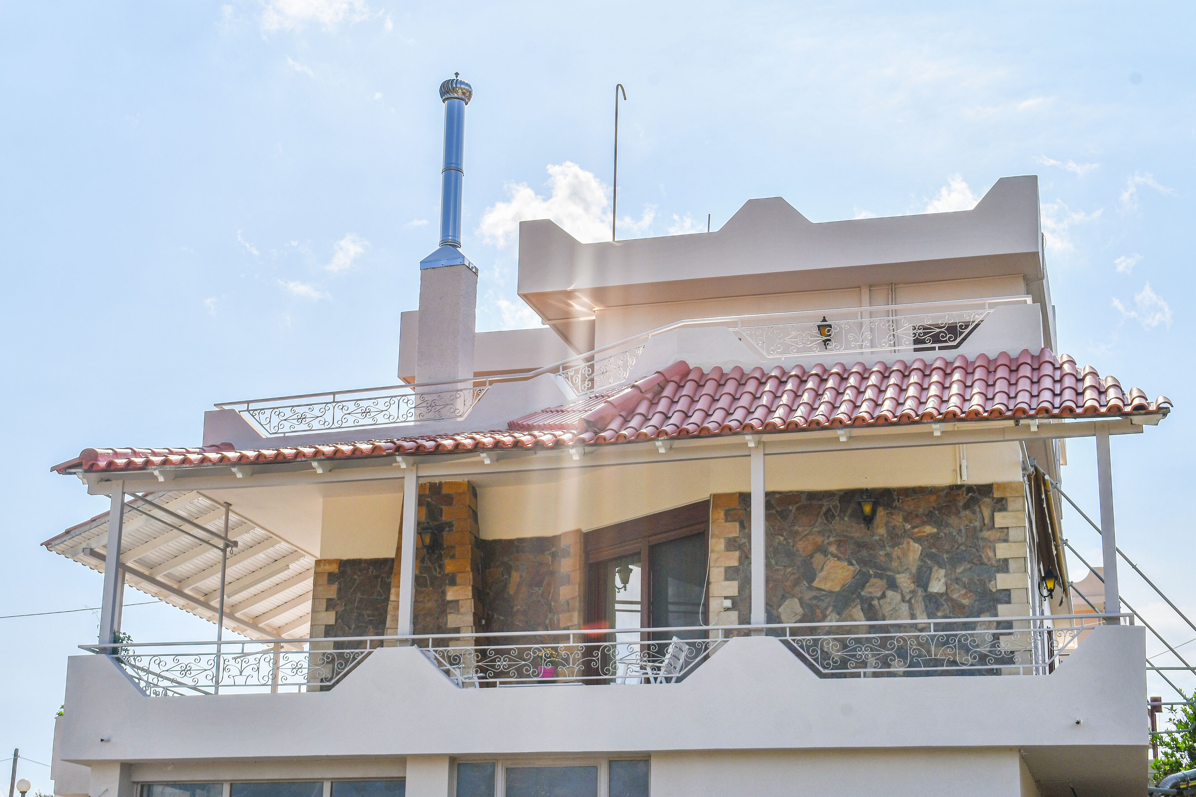 A multi-story building with a balcony, stone facade, and a chimney.