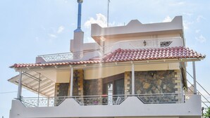 Un edificio de varios pisos con balcón, fachada de piedra y chimenea.