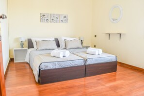 Un letto matrimoniale con una testiera scura, due comodini con lampade e uno specchio fissato alla parete.