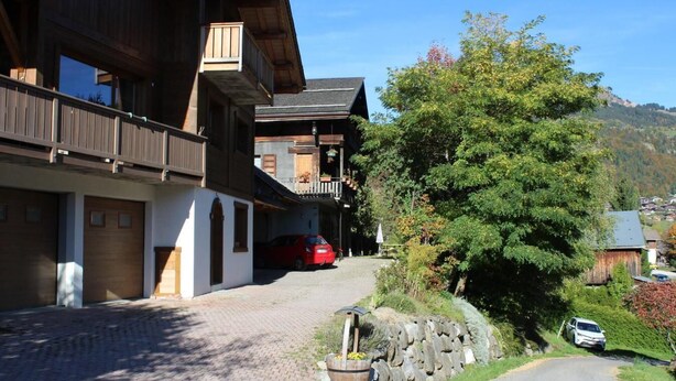 Un edificio de madera tradicional con un balcón, una pared de piedra y un camino pavimentado.