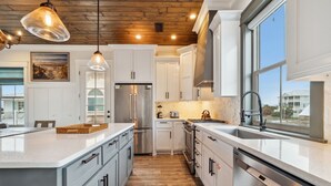 A modern kitchen with white cabinets, stainless steel appliances, and a large island.