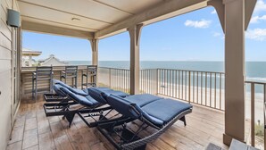 A covered outdoor area with lounge chairs and a view of the beach.
