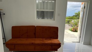 Una habitación con sofá, ventana y vistas al exterior.