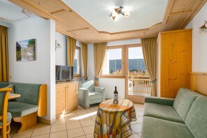 Een gezellige woonkamer met een bank, een stoel, een kleine tafel met een fles en een televisie op een houten kast.