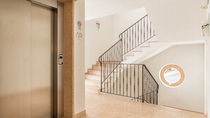A staircase with a metal railing, a door with a handle, and a circular window on the wall. - 'Residence Diana Apartment 101' with Mountain View, Balcony & Wi-Fi (Terenten)