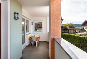 Ein Balkon mit Tisch und Stühlen, ein Fenster und Blick auf die Umgebung.