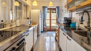 A modern kitchen with stainless steel appliances, a central island, and a view through a glass door.
