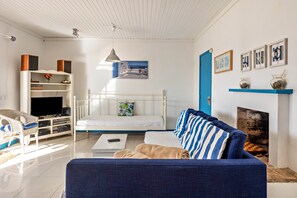 A living room with a white bed, blue sofa, and a fireplace.