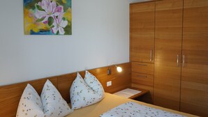 Ein Schlafzimmer mit einem Holzkopfteil, einem Bett mit floralem Bettbezug, einem Nachttisch und einem Holzschrank.