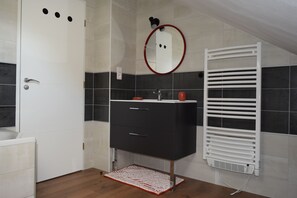 A modern bathroom with a white vanity, a round mirror, and a white towel rack. - Le Quiet Gîte à la Campagne (Charbonnières-les-Vieilles)