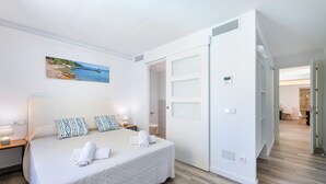 A hotel room with a bed, a painting, a wardrobe, and a bathroom.