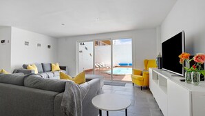 A modern living room with a grey sofa, a small white table, a flat-screen TV, and a yellow armchair. - 'Villa Pacifica' with heated pool, terrace, lounge area & Wi-Fi (Corralejo)
