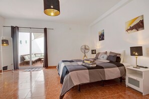 A bedroom with a bed, bedside lamps, a fan, and a view through a sliding door.