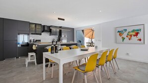 A modern kitchen with grey cabinets, a white countertop, and a dining area with a white table and yellow chairs. - 'Villa Pacifica' with heated pool, terrace, lounge area & Wi-Fi (Corralejo)