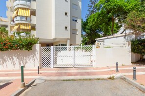 A gated residential area with a white building, a gated entrance, and a clear sky.