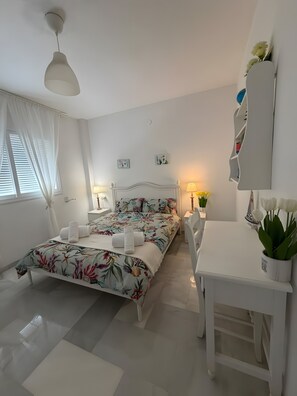A hotel room with a bed, bedside tables, a desk, and a chair.