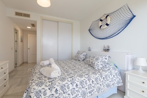 A bedroom with a bed, a nightstand, a dresser, a wall-mounted life preserver, and a door.