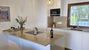 A modern kitchen with a central island, a microwave, a sink, and a window with a view of trees. - Family-Friendly Vacation Home 'Casa Sirena' with 2 Terraces & Wi-Fi (Empuriabrava)