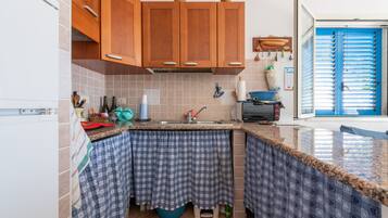 A kitchen with wooden cabinets, a sink, and a window with blinds.